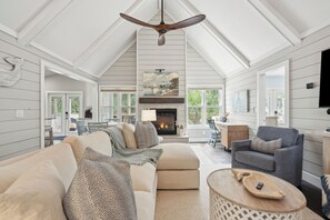 Ein geräumiges Wohnzimmer mit hoher Decke, Kamin und großem Fenster.