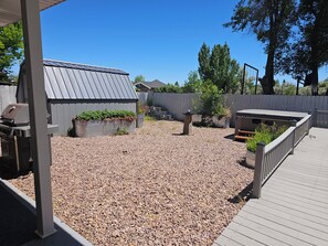 A backyard with a barbecue area, a covered patio, and a wooden deck.
