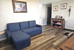 A living room with a blue sofa, a bookshelf with books, and framed pictures on the wall.