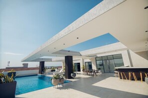 Ein Poolbereich auf dem Dach mit modernem Design, inklusive Pool, Sitzgelegenheiten und einer Bar.