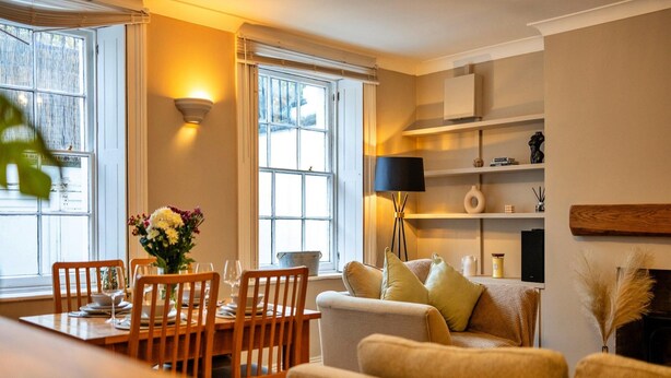 A well-lit living room with a dining area, large windows, and a fireplace. - Elegant Apartment in Regency Cheltenham (Cheltenham)