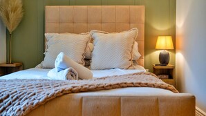 A bed with a headboard, pillows, and a blanket. There is a lamp on a bedside table. - Elegant Apartment in Regency Cheltenham (Cheltenham)