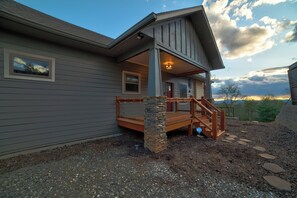 A residential building with a stone staircase leading to a wooden deck, a covered porch, and a view of the surrounding landscape. - Sunset Views (Blairsville)