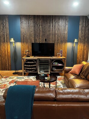 A living room with a flat-screen TV, leather sofa, and a patterned rug. - Sunset Views (Blairsville)