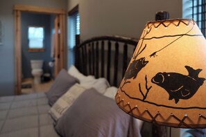 A lamp with a fish design on a bed in a room with a wooden headboard and a visible door. - Sunset Views (Blairsville)