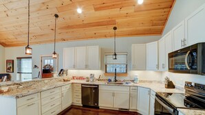 A spacious kitchen with wooden cabinets, a stainless steel dishwasher, and a large oven. - Sunset Views (Blairsville)