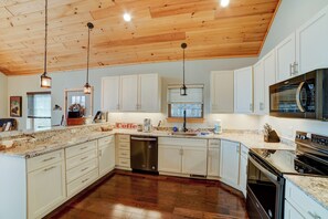 A spacious kitchen with wooden cabinets, a stainless steel dishwasher, and a large oven. - Sunset Views (Blairsville)