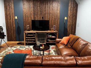 A living room with a leather sofa, a coffee table, a TV, and a wooden entertainment unit. - Sunset Views (Blairsville)