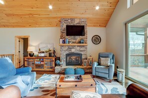 A cozy living room with a stone fireplace, a mounted television, and comfortable seating. - Sunset Views (Blairsville)