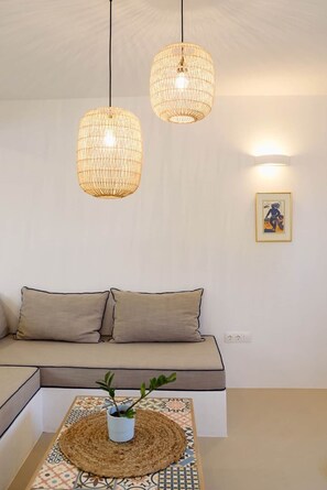 Ein Wohnzimmer mit einer Couch, zwei hängenden Korbstühlen, einer Wandleuchte und einem gerahmten Bild.