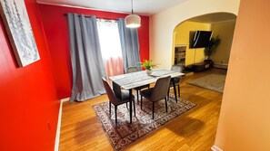 A dining area with a table, chairs, and a rug.