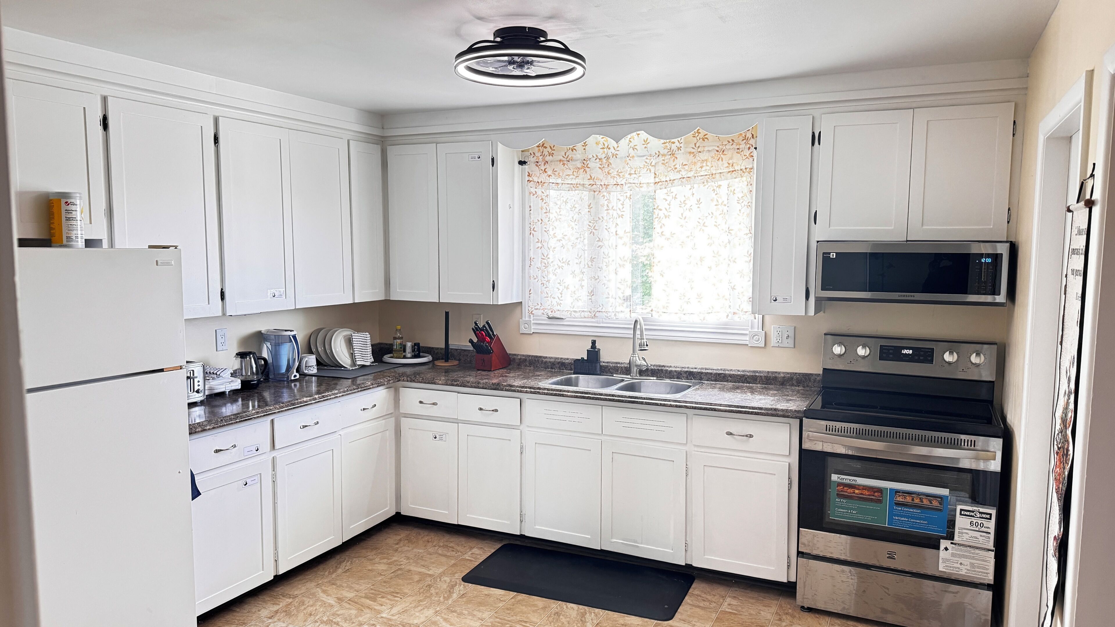 A kitchen with white cabinets, a microwave, an oven, and a sink.