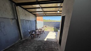 Eine überdachte Terrasse im Freien mit Backsteinböden und Metallmöbeln.