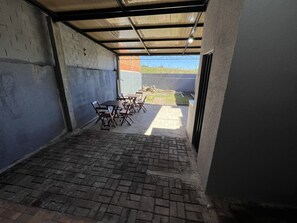 Un patio techado al aire libre con suelo de ladrillo y mesas y sillas de metal.