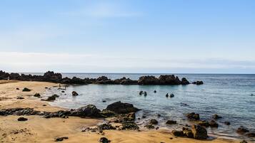 A beach with rocky outcrops and calm waters.