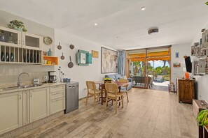 A modern kitchen with a dining area, a coffee machine, and a view through a glass door to an outdoor space. - Holiday Apartment 'Casa Sherazad' with Sea View, Private Terrace and Wi-Fi (Tías)