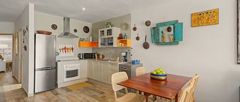 A kitchen with a dining area, wooden flooring, and various kitchen appliances.