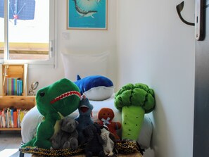 A room with a bed, stuffed toys, a bookshelf, and a framed picture on the wall.