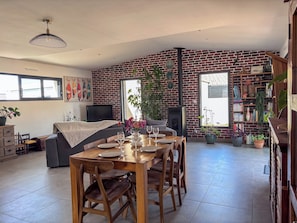 A dining area with a brick wall, a fireplace, and a bookshelf.