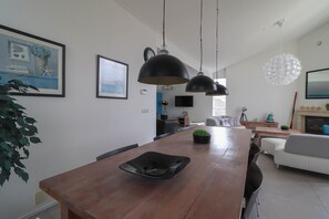 Ein modernes Wohnzimmer mit einem Holzesstisch, schwarzen Pendelleuchten und einem weißen Sofa.