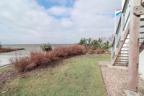 A coastal property with a grassy lawn, a wooden staircase, and a flag on a building. - Beach Villa With Sauna for 8 Guests (Makkum)