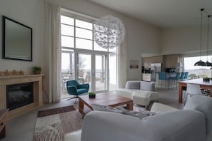 Ein geräumiges Wohnzimmer mit Kamin, Esstisch und einer Küche im Hintergrund.