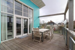 Un espacio al aire libre techado con una mesa, sillas, un acceso con puerta de vidrio y vistas del vecindario.