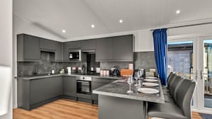 Una cocina moderna con armarios grises, una isla central y una zona de comedor con un sofá gris.