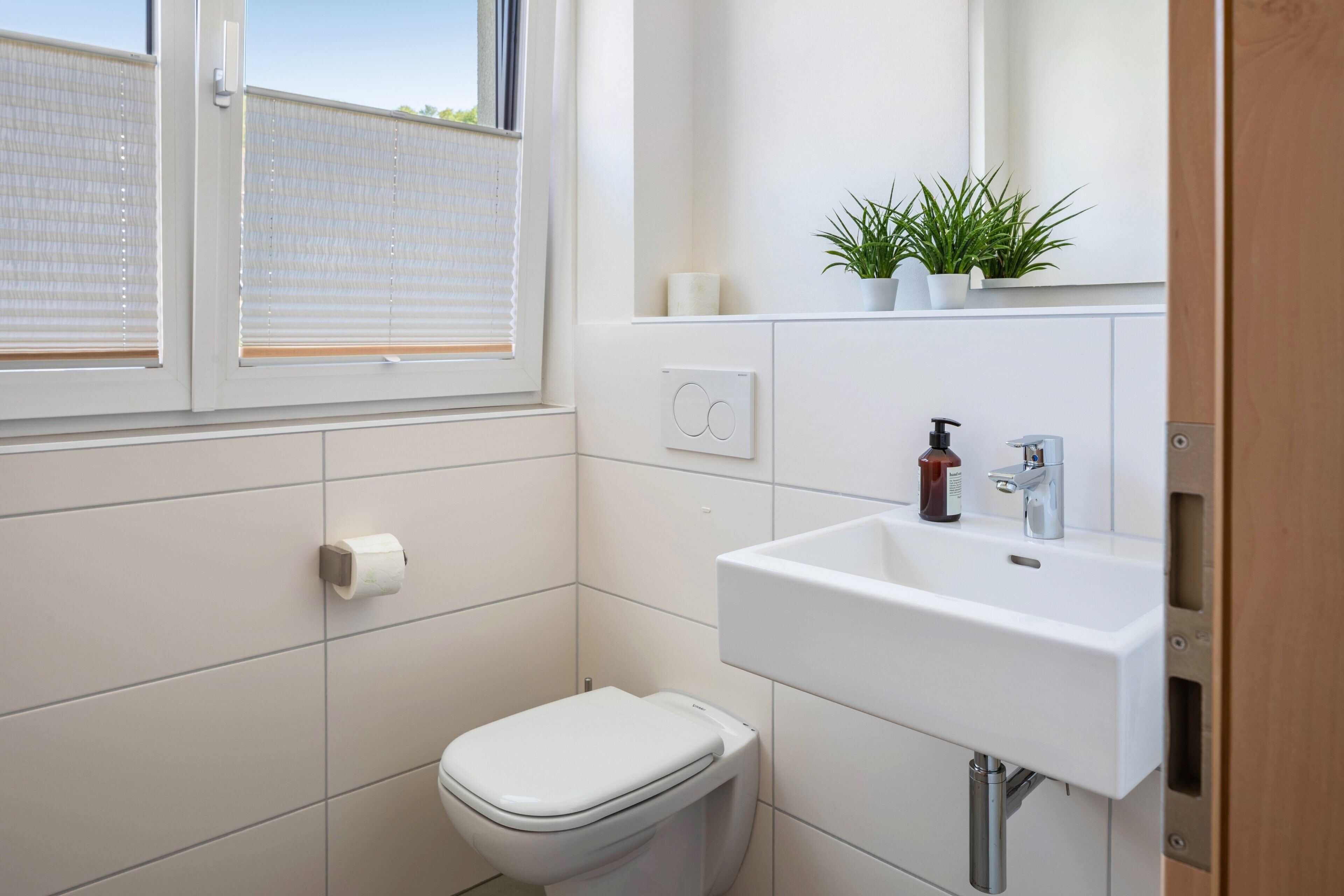 Ein modernes Badezimmer mit Toilette, Waschbecken und Fenster.