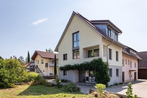 A two-story residential building with a sloped roof, a balcony, and a small garden area with a table and chairs. - Modern Holiday Home Paula with Pool at the Kaiserstuhl (Ihringen)