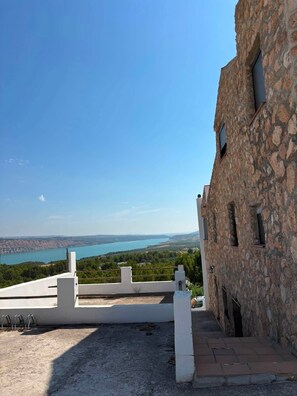 A stone building with a view of a lake and distant hills.