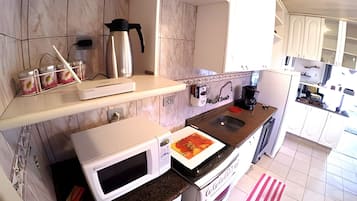 Una cocina equipada con microondas, horno, cafetera y escurreplatos.