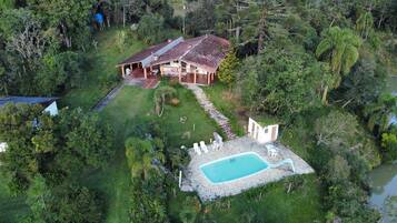 A house with a swimming pool surrounded by lush greenery.