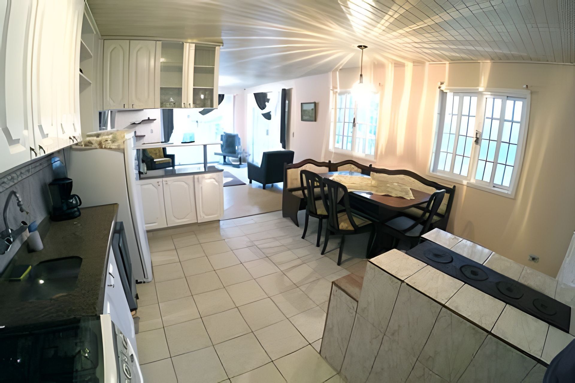 A kitchen with white cabinets, a dining area with a table and chairs, and a window with a view.