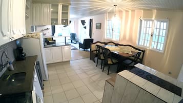 A kitchen with white cabinets, a dining area with a table and chairs, and a window with a view.