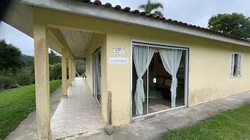 A building with a covered walkway, a door with curtains, and a sign.