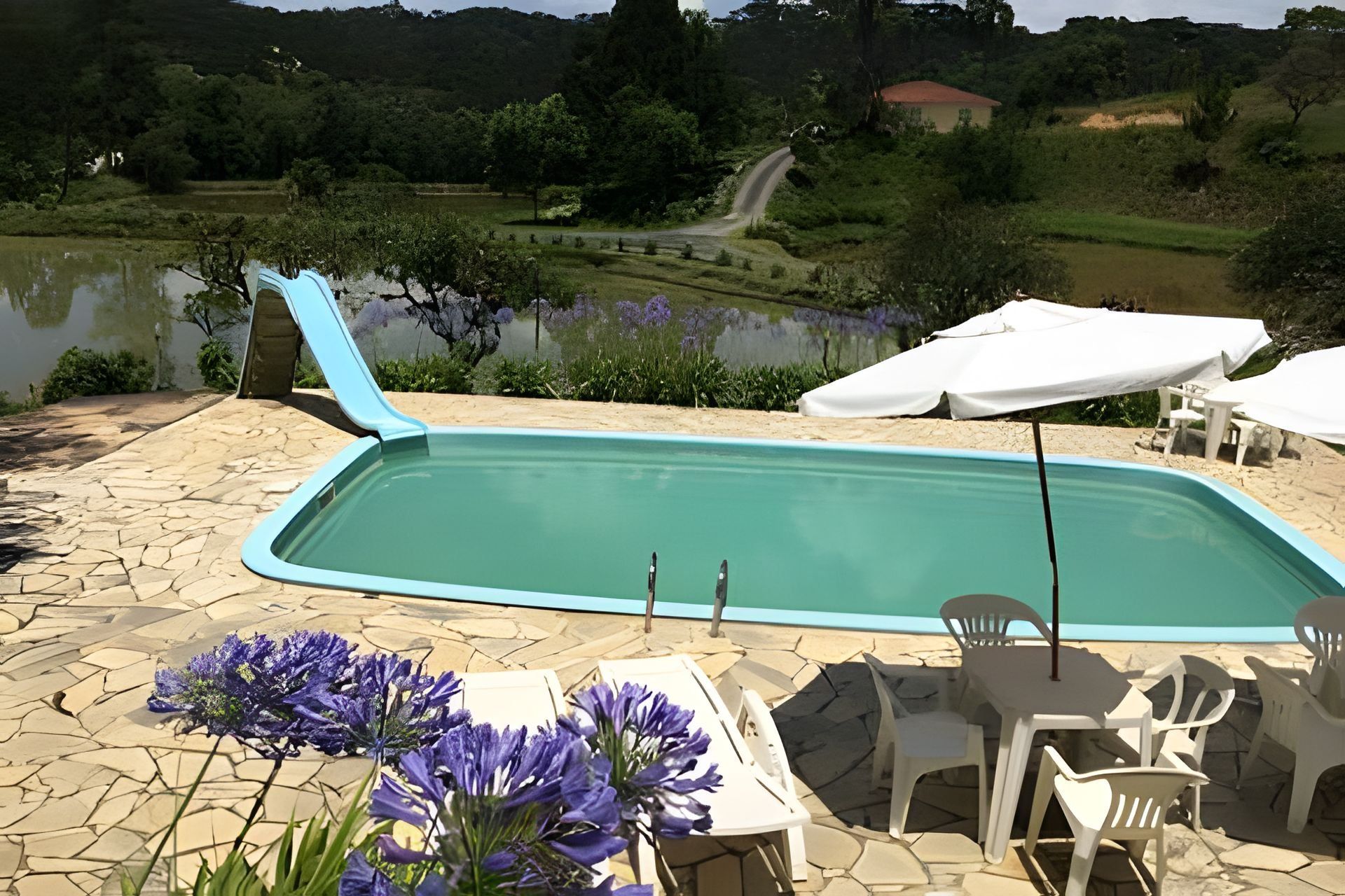 A swimming pool with a view of a lake and hills in the background.