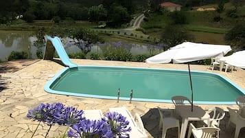 A swimming pool with a view of a lake and hills in the background.