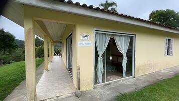 A building with a covered walkway, a door with curtains, and a sign.
