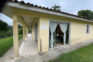 A building with a covered walkway, a door with curtains, and a sign.