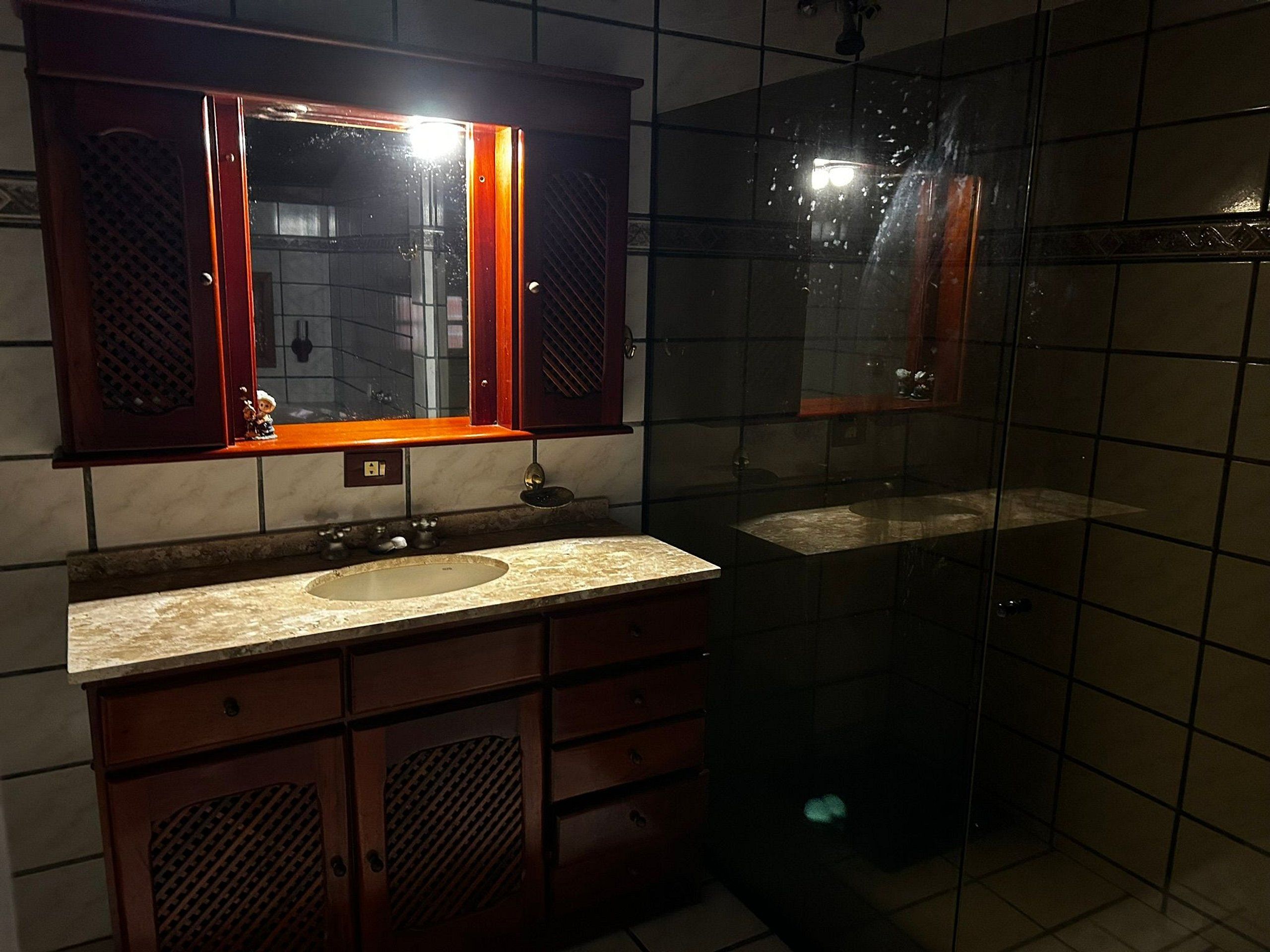Un baño con lavamanos, espejo y ducha.