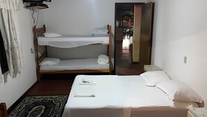Quarto com beliches, escrivaninha, cadeira e televisão.