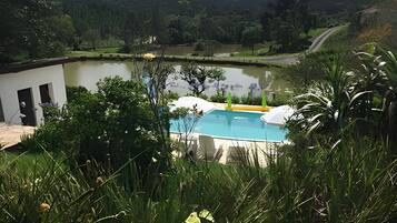 A swimming pool with a view of a lake and hills in the background.