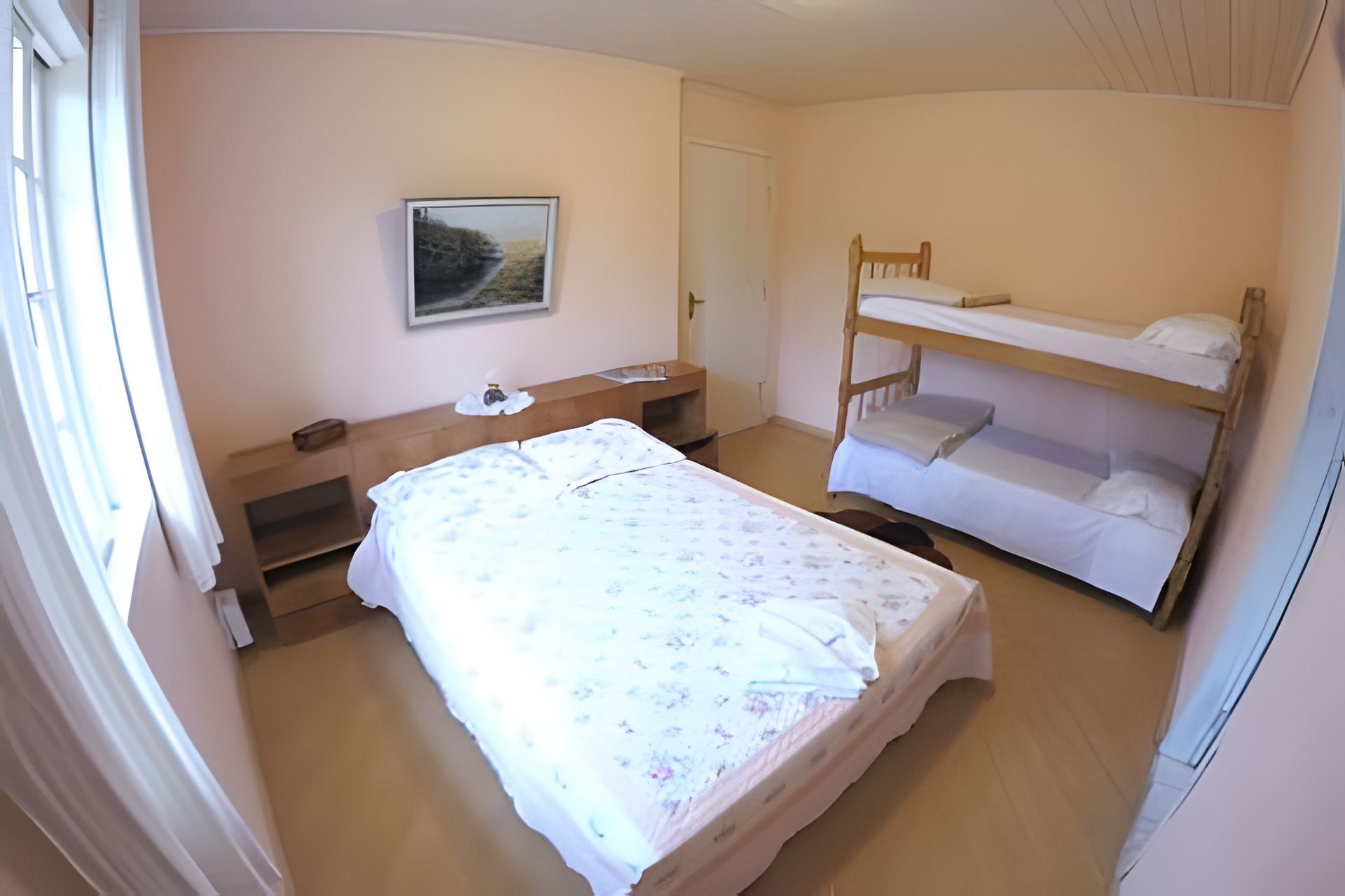 A bedroom with a single bed, a bunk bed, a bedside table, and a wall-mounted picture.