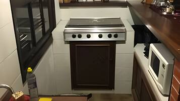 A compact kitchen with a stove, oven, microwave, and sink.