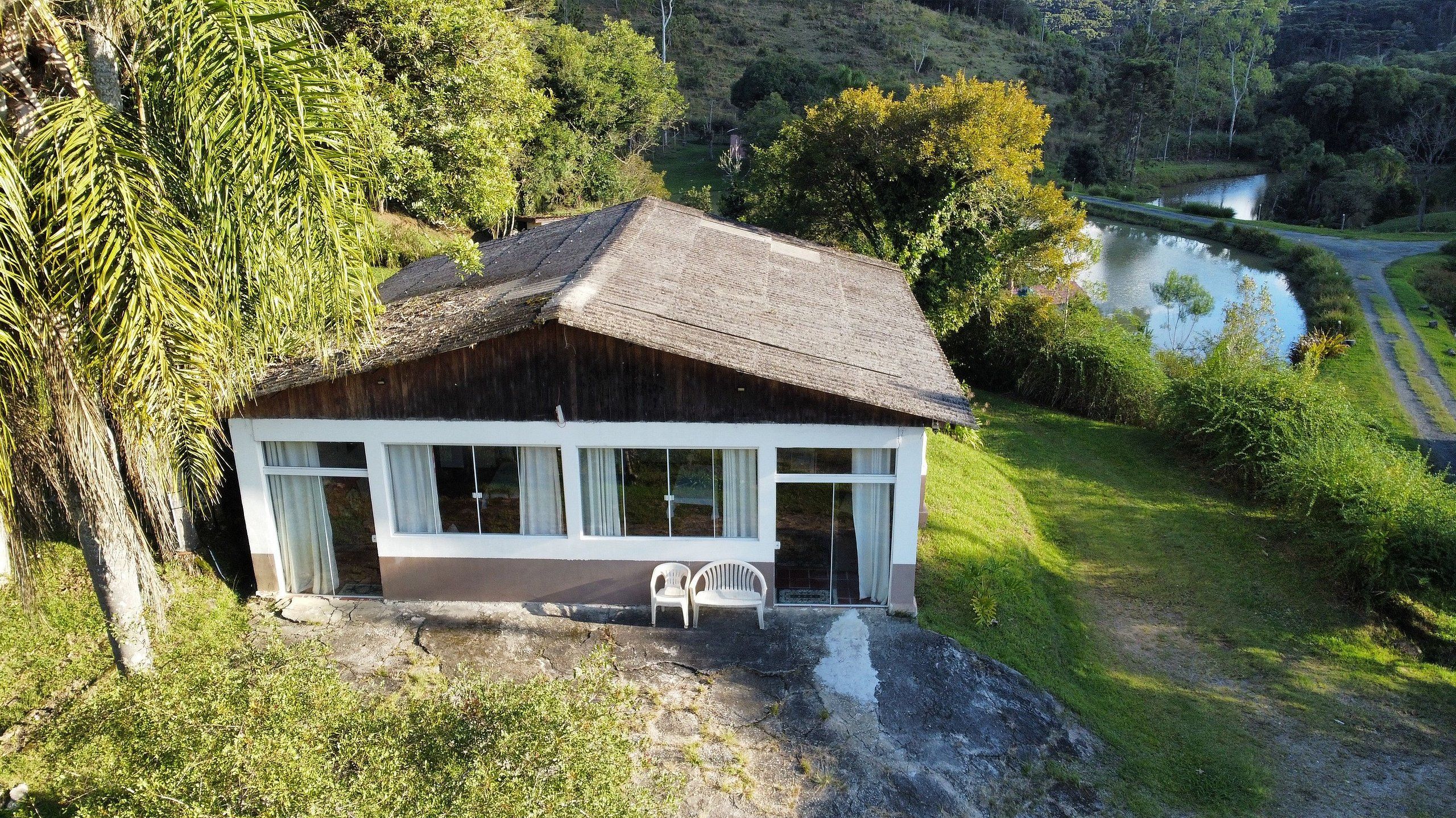 A rustic cabin with a sloped roof, large windows, and a small porch with two chairs.