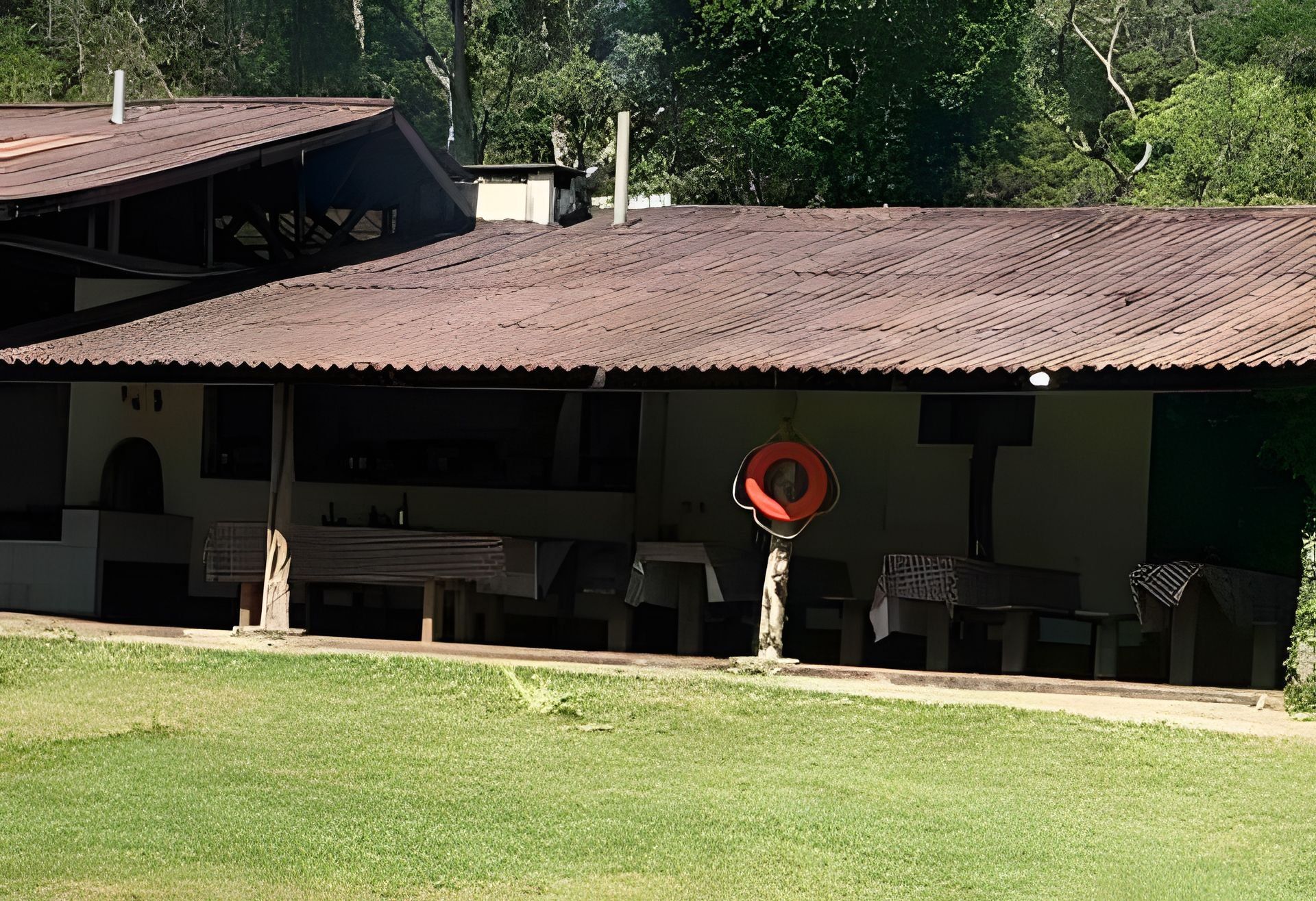 A building with a covered patio area, outdoor seating, and a red circular object on the roof.