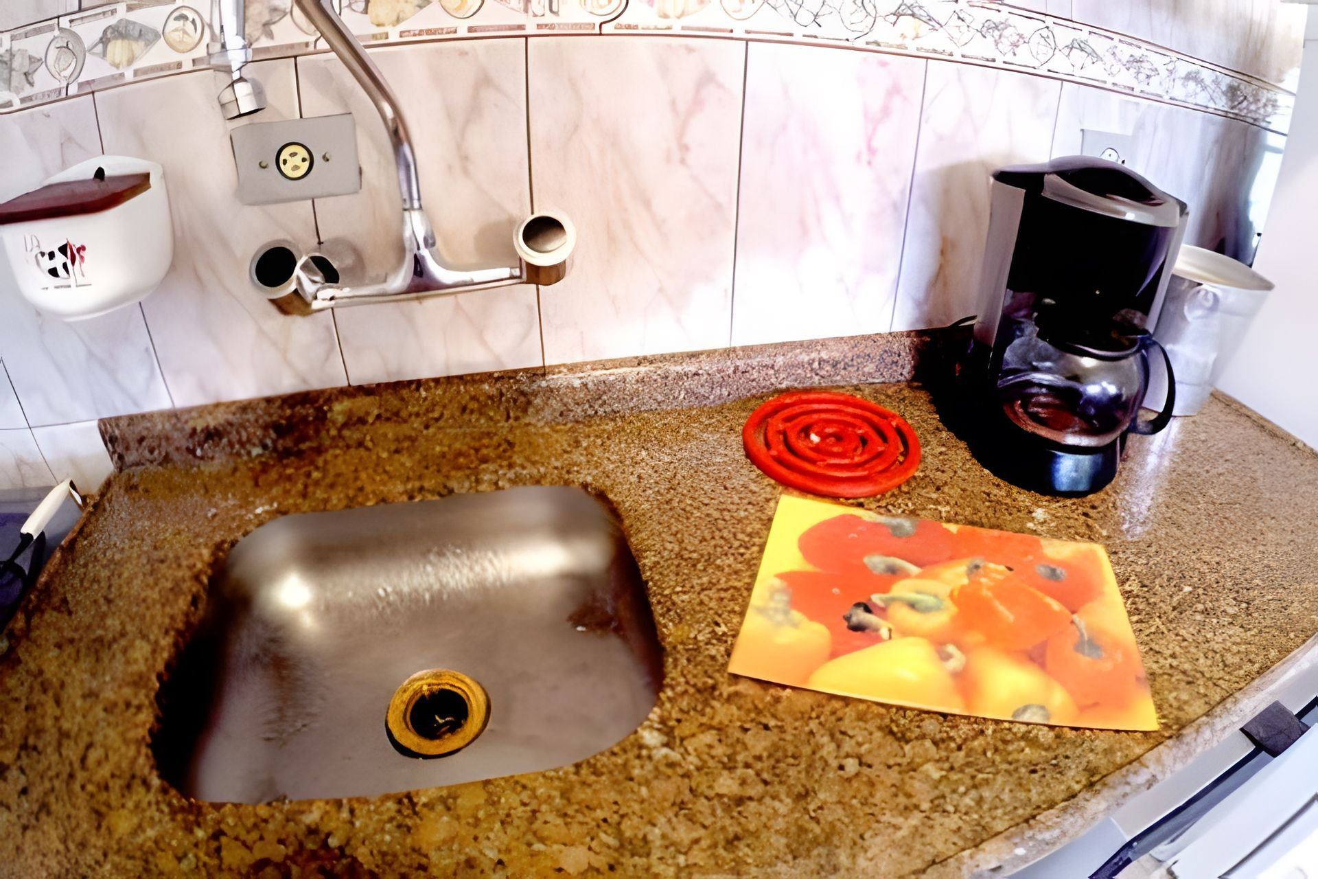 A kitchen with a sink, a coffee maker, and a cutting board with vegetables.