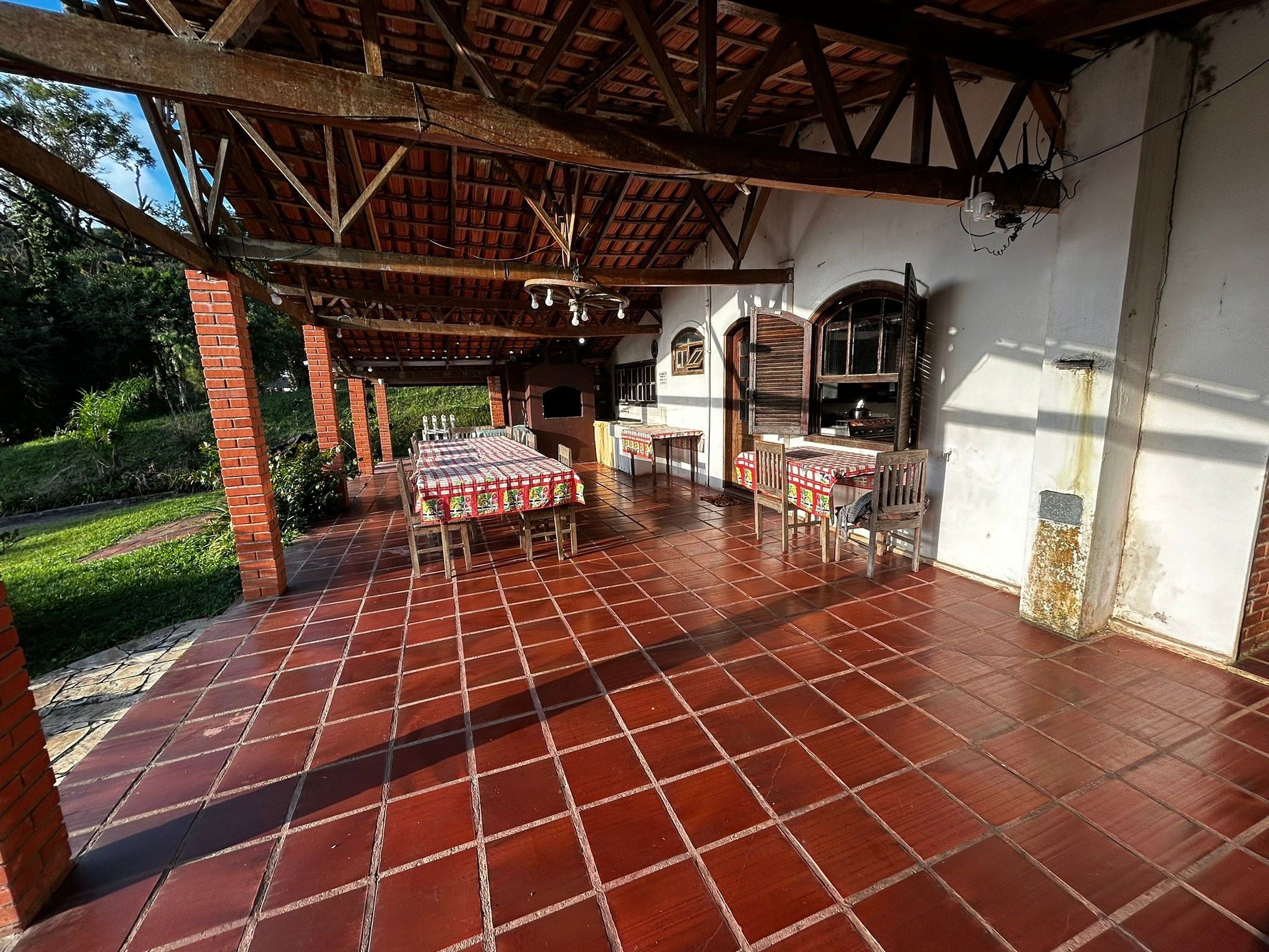 An outdoor patio with a tiled floor, a covered seating area, and a brick wall.