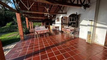 An outdoor patio with a tiled floor, a covered seating area, and a brick wall.